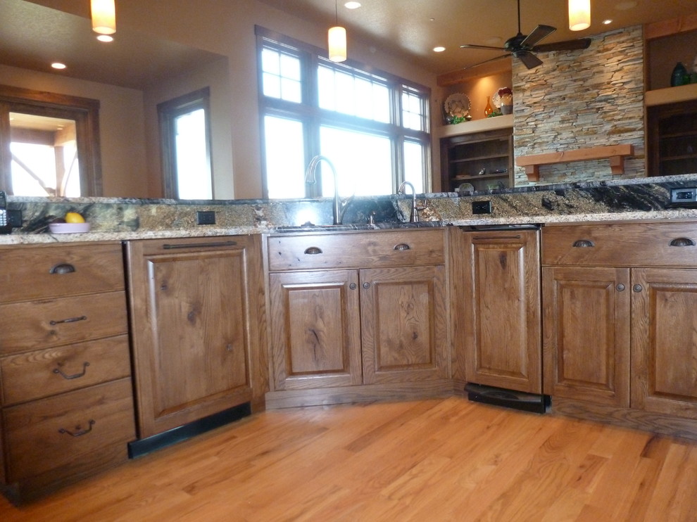 Inspiration for a large rustic l-shaped medium tone wood floor eat-in kitchen remodel with an undermount sink, raised-panel cabinets, dark wood cabinets, granite countertops, multicolored backsplash, matchstick tile backsplash, stainless steel appliances and an island