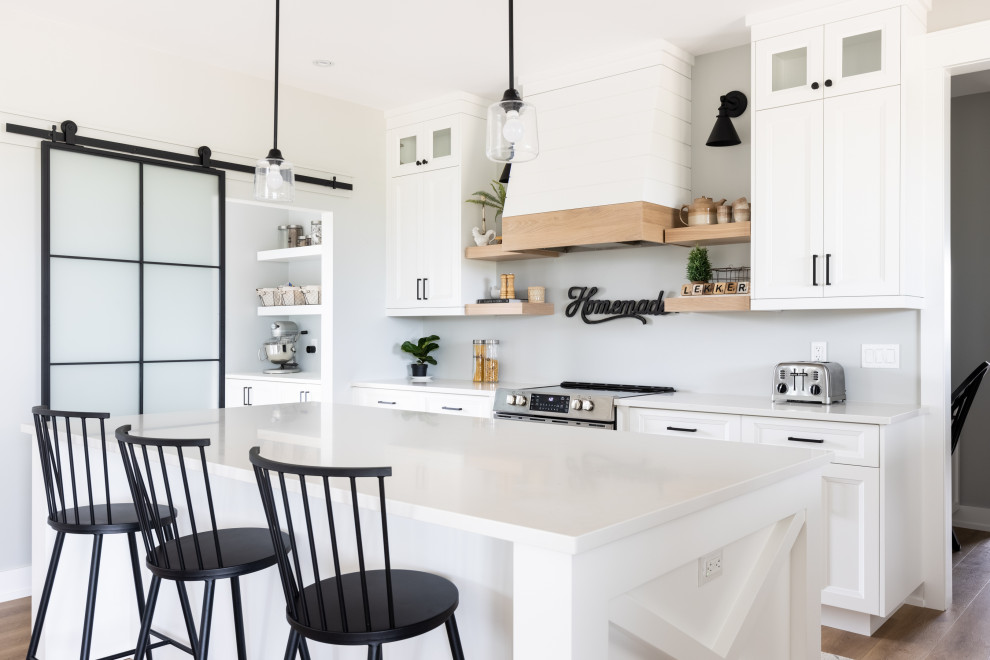 Photo of a mid-sized transitional l-shaped eat-in kitchen in Other with an undermount sink, shaker cabinets, white cabinets, quartz benchtops, shiplap splashback, stainless steel appliances, medium hardwood floors, with island, multi-coloured floor, white benchtop and vaulted.