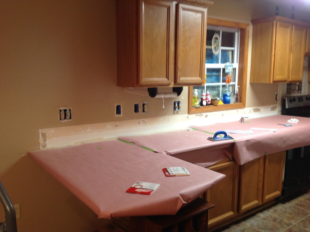 L-shaped eat-in kitchen photo with an undermount sink, flat-panel cabinets, brown backsplash, glass tile backsplash, stainless steel appliances and a peninsula