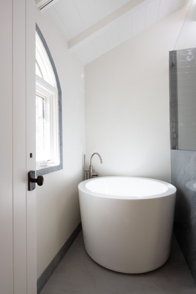 Пример оригинального дизайна: большая ванная комната в морском стиле с плоскими фасадами, светлыми деревянными фасадами, японской ванной, душем в нише, унитазом-моноблоком, серой плиткой, стеклянной плиткой, серыми стенами, мраморным полом, настольной раковиной, мраморной столешницей, серым полом, серой столешницей, сиденьем для душа, тумбой под одну раковину и подвесной тумбой