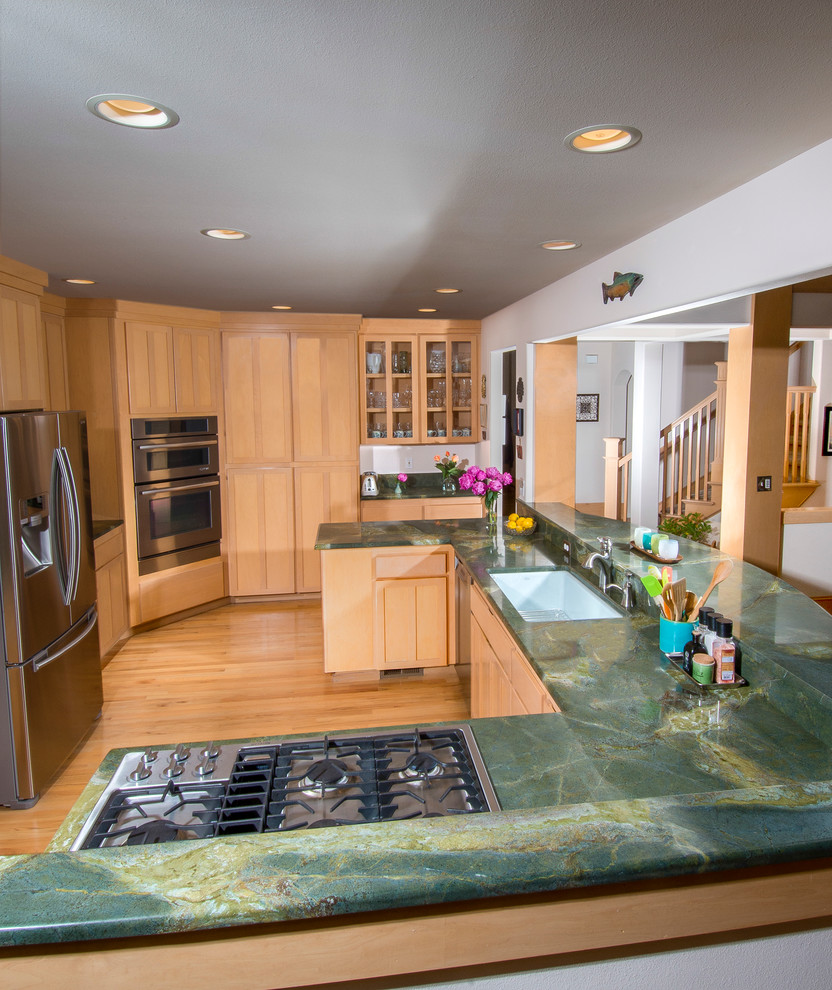 Large transitional u-shaped open plan kitchen in Seattle with an undermount sink, shaker cabinets, light wood cabinets, granite benchtops, stainless steel appliances, light hardwood floors, a peninsula, beige floor and green benchtop.