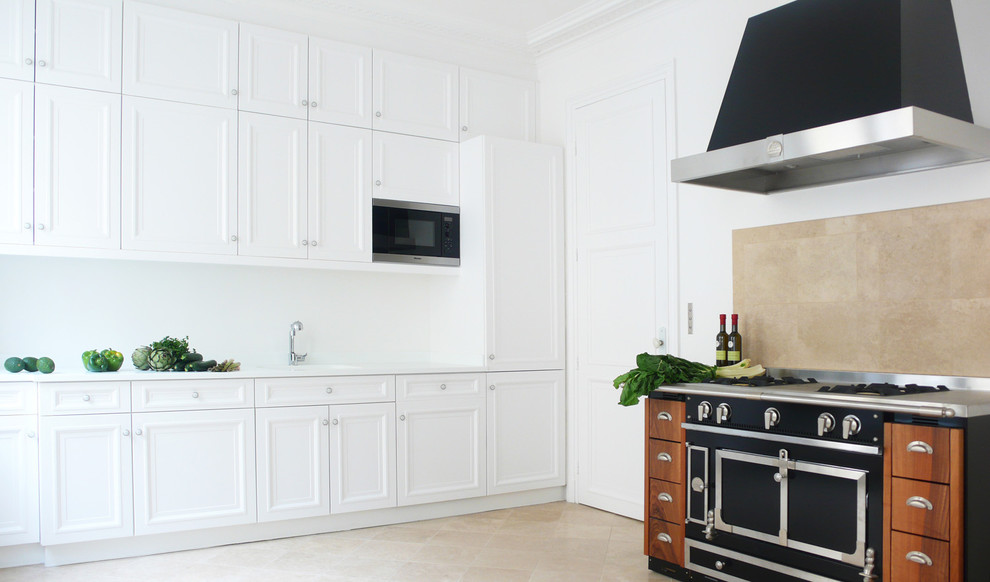 Large traditional l-shaped separate kitchen in Paris with an integrated sink, beaded inset cabinets, white cabinets, beige splashback, black appliances, travertine floors and ceramic splashback.