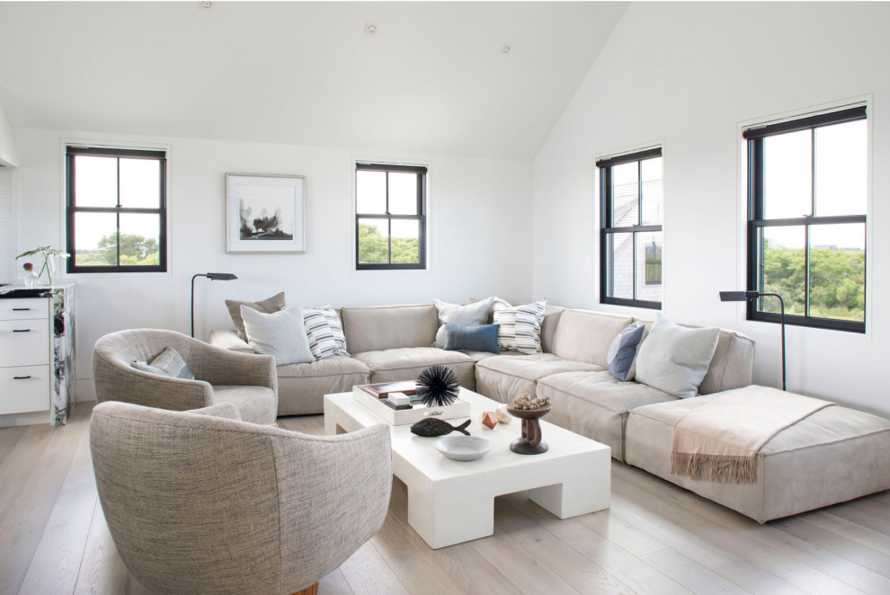 This is an example of a beach style living room in Boston with white walls, light hardwood floors, no fireplace and beige floor.