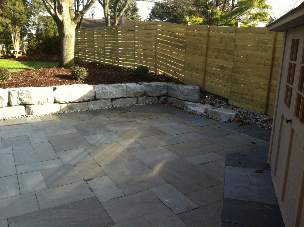 Photo of a mid-sized contemporary backyard patio in Toronto with natural stone pavers and no cover.