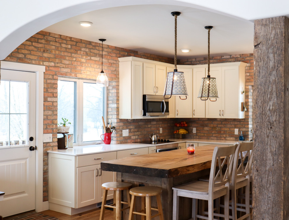 This is an example of a mid-sized traditional kitchen/dining combo in Grand Rapids with beige walls, light hardwood floors and brick walls.