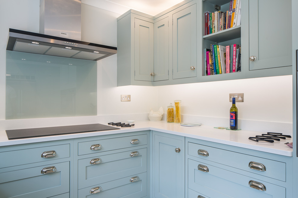 Mid-sized contemporary u-shaped eat-in kitchen in Oxfordshire with a drop-in sink, shaker cabinets, turquoise cabinets, laminate benchtops, white splashback, glass sheet splashback, stainless steel appliances, slate floors, a peninsula and white floor.