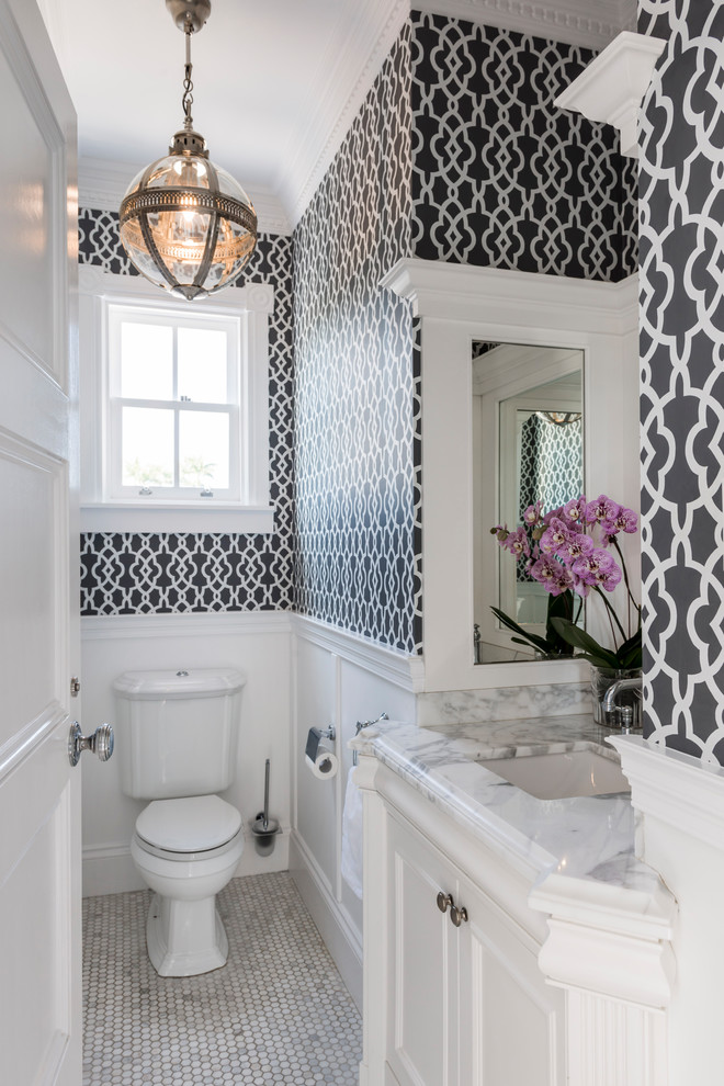 Photo of a traditional powder room in Brisbane with recessed-panel cabinets, white cabinets, a two-piece toilet, mosaic tile floors, an undermount sink and grey floor.