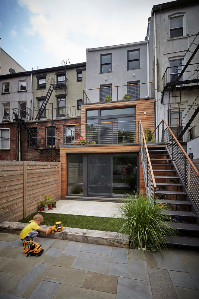 This is an example of a mid-sized contemporary three-storey grey townhouse exterior in New York with wood siding and a flat roof.