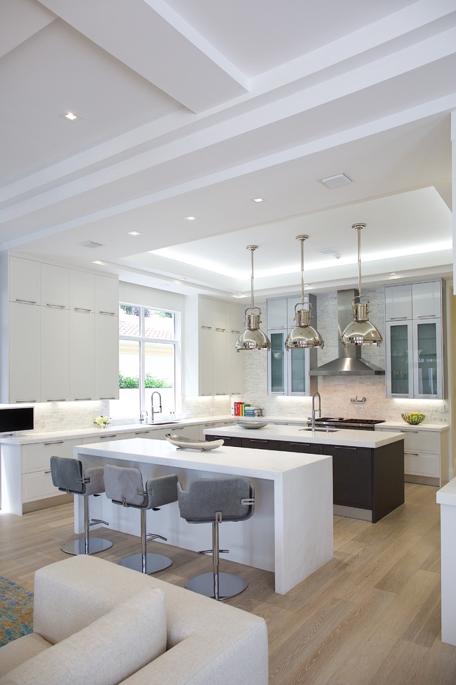 Design ideas for a large contemporary u-shaped eat-in kitchen in Miami with a single-bowl sink, glass-front cabinets, white cabinets, solid surface benchtops, grey splashback, stone tile splashback, panelled appliances, ceramic floors and multiple islands.