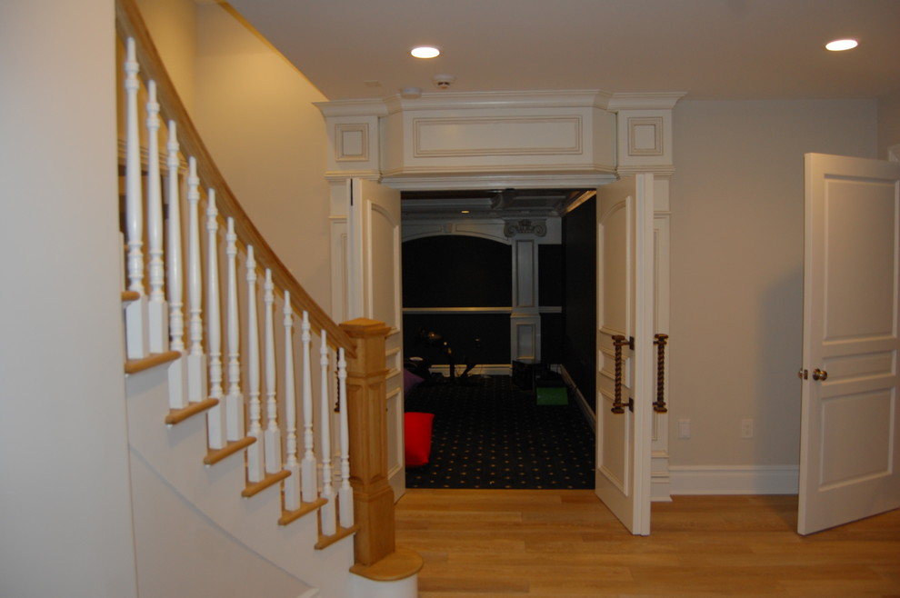 Photo of an expansive traditional look-out basement in New York with beige walls, light hardwood floors, a two-sided fireplace and beige floor.