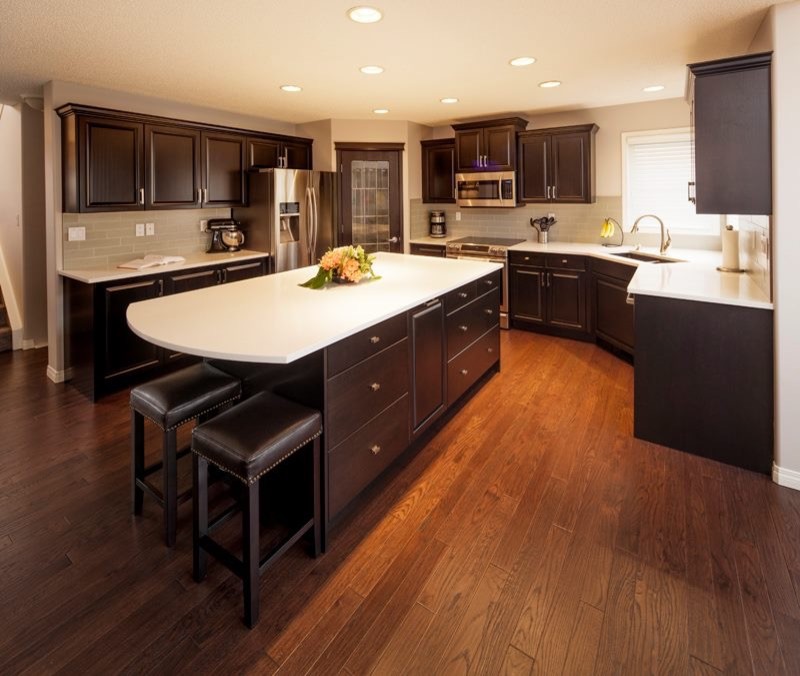 Large transitional u-shaped dark wood floor and brown floor eat-in kitchen photo in Calgary with a double-bowl sink, raised-panel cabinets, dark wood cabinets, quartz countertops, gray backsplash, ceramic backsplash, stainless steel appliances and an island
