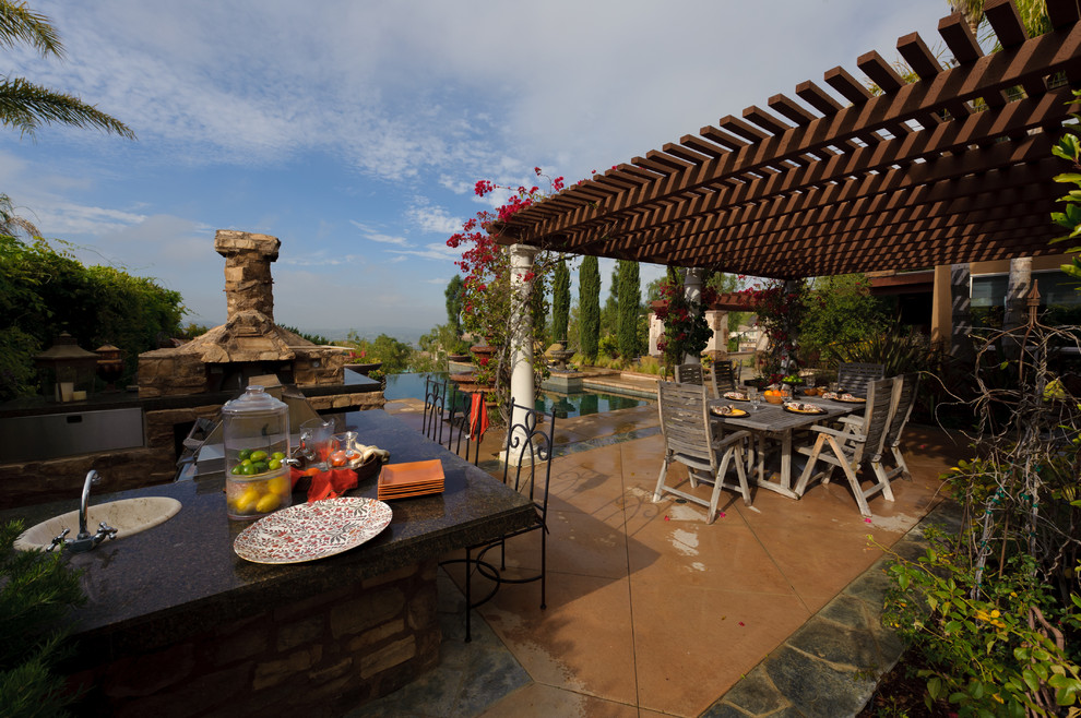 Immagine di un grande patio o portico mediterraneo dietro casa con lastre di cemento e una pergola