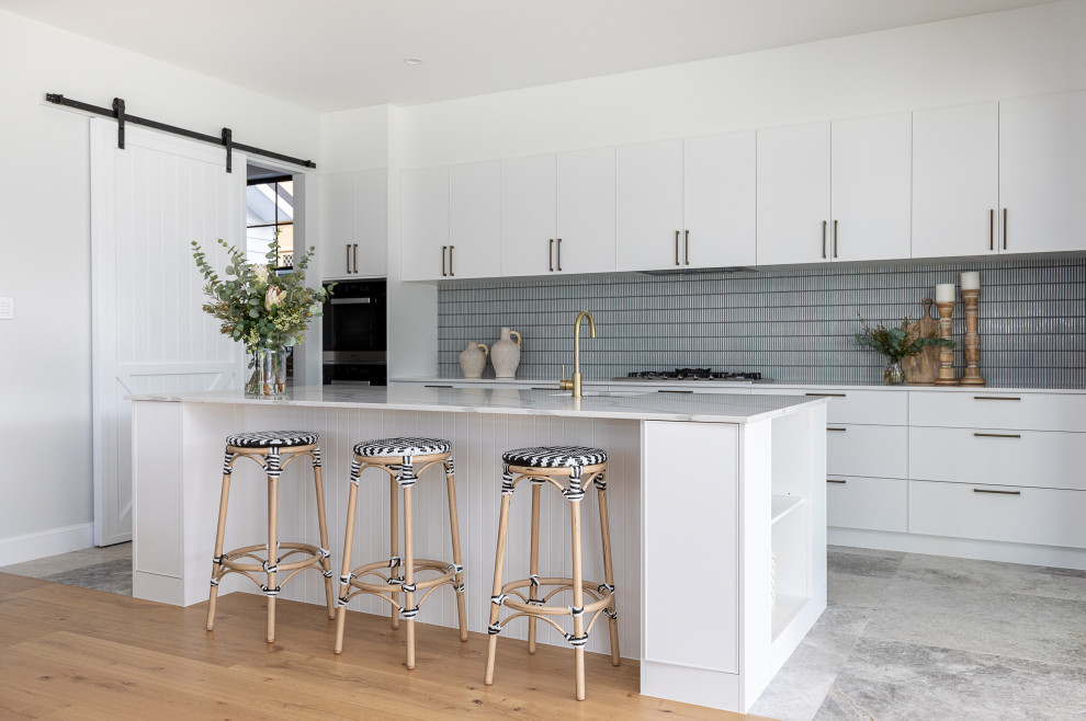 Inspiration for a contemporary galley kitchen in Brisbane with an undermount sink, flat-panel cabinets, white cabinets, grey splashback, subway tile splashback, with island, grey floor and white benchtop.