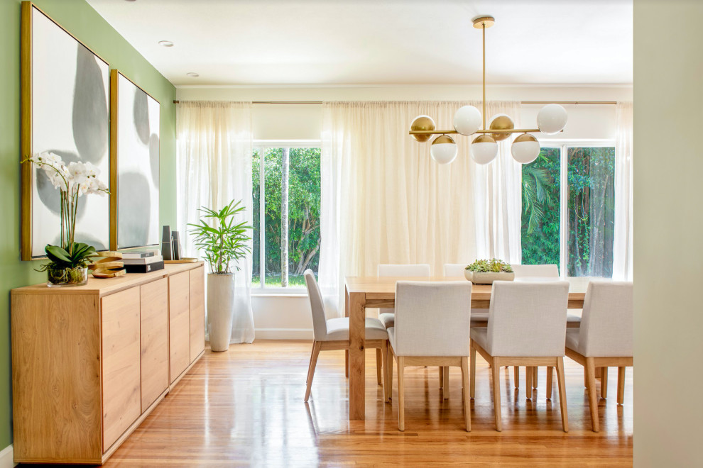 Photo of a mid-sized contemporary kitchen/dining combo in Miami with green walls, no fireplace, brown floor and medium hardwood floors.