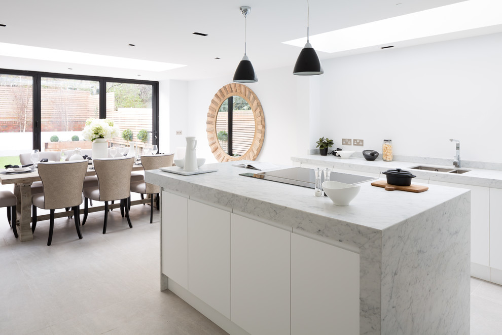 Inspiration for a small transitional open plan kitchen in London with a drop-in sink, flat-panel cabinets, white cabinets, marble benchtops, white splashback, porcelain floors and with island.