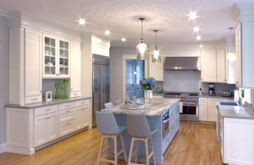 Open concept kitchen - large transitional u-shaped light wood floor and brown floor open concept kitchen idea in Boston with an undermount sink, shaker cabinets, white cabinets, quartz countertops, stainless steel appliances and an island