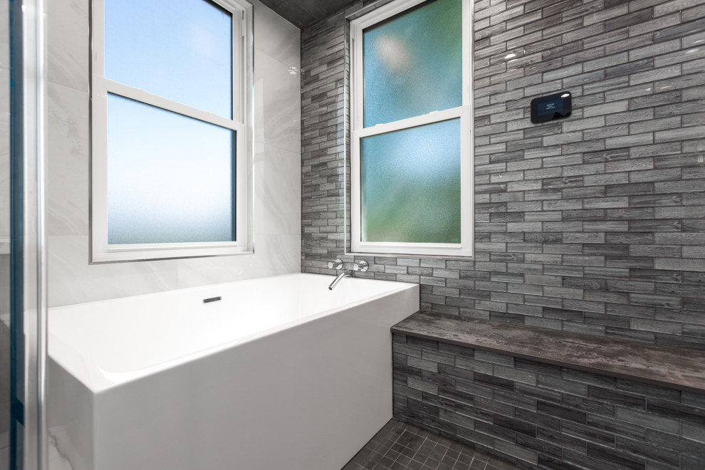 This is an example of a mid-sized contemporary master bathroom in DC Metro with flat-panel cabinets, grey cabinets, a freestanding tub, gray tile, glass tile, porcelain floors, an undermount sink, engineered quartz benchtops, white floor, white benchtops, a double vanity and a built-in vanity.