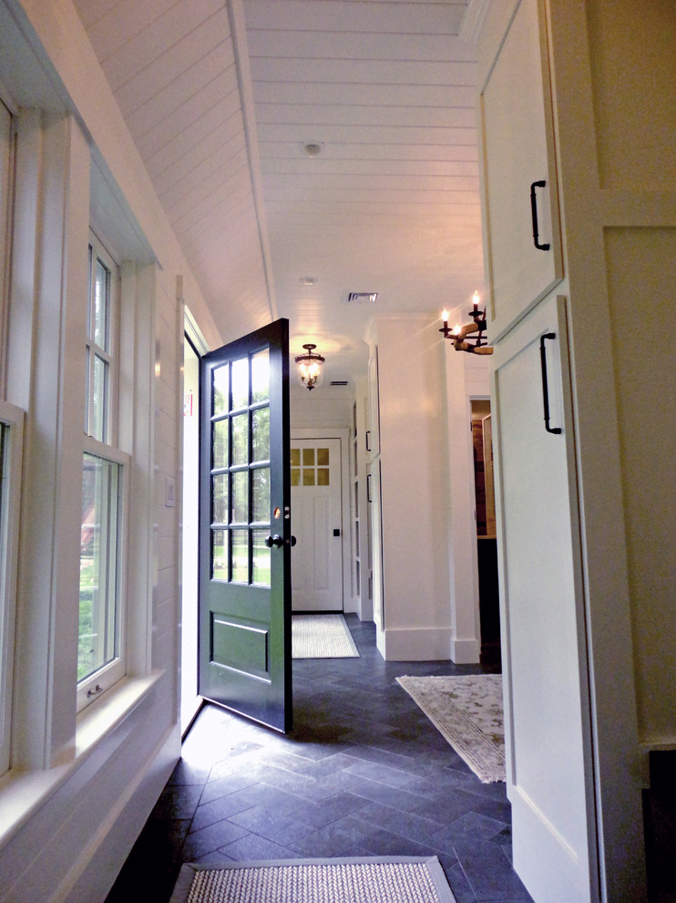 Photo of a large country mudroom in Boston with white walls, black floor, granite floors, a pivot front door and a green front door.