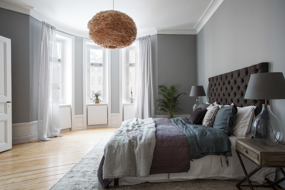 This is an example of a mid-sized scandinavian master bedroom in Stockholm with grey walls and light hardwood floors.