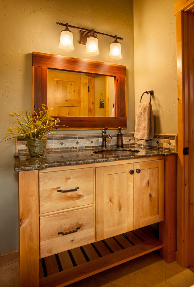 Photo of a mid-sized country master bathroom in Portland with shaker cabinets, brown cabinets, brown tile, mosaic tile, porcelain floors, an undermount sink, granite benchtops, brown floor and black benchtops.