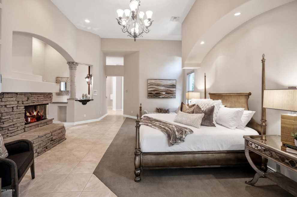 This is an example of a large traditional master bedroom in Phoenix with beige walls and a corner fireplace.