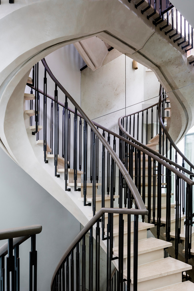 На фото: изогнутая бетонная лестница среднего размера в стиле фьюжн с мраморными ступенями и металлическими перилами