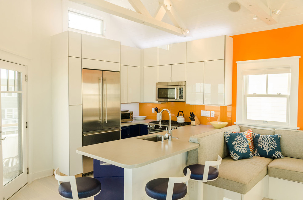 Beach style u-shaped open plan kitchen in Philadelphia with an undermount sink, flat-panel cabinets, white cabinets, orange splashback, stainless steel appliances, a peninsula and beige floor.