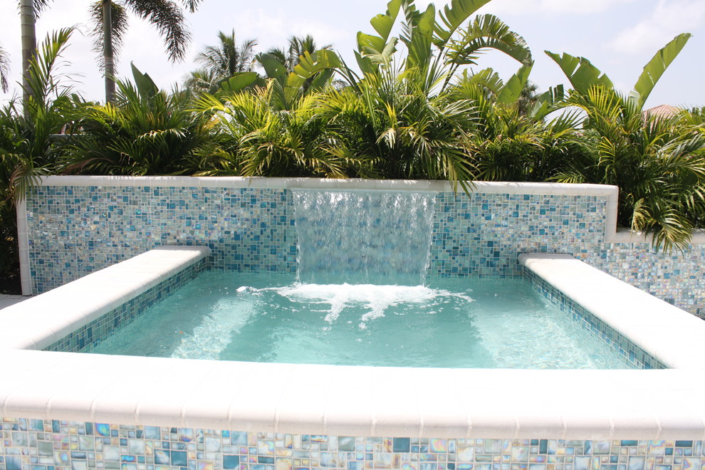 This is an example of a small modern backyard rectangular aboveground pool in Miami with a hot tub and concrete pavers.