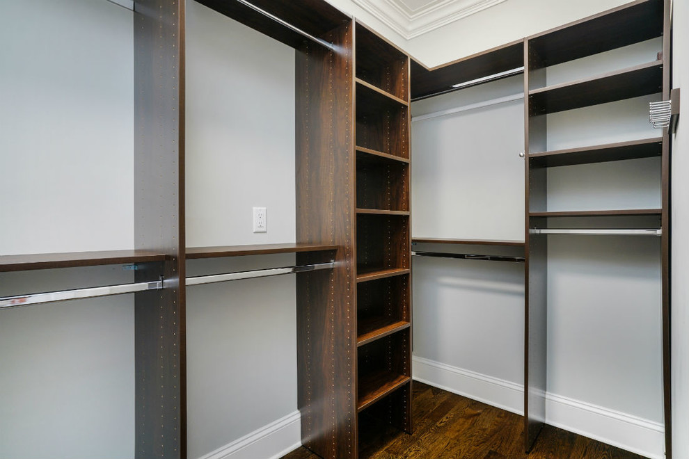Mid-sized traditional gender-neutral walk-in wardrobe in New York with open cabinets, dark wood cabinets, dark hardwood floors and brown floor.