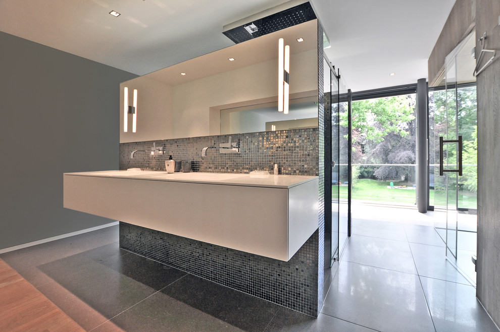 Expansive contemporary bathroom in Dusseldorf with flat-panel cabinets, white cabinets, an alcove shower, blue tile, gray tile, mosaic tile, grey walls and an integrated sink.