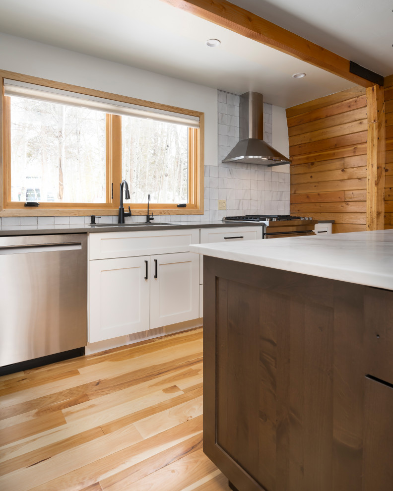 Esempio di una cucina minimal di medie dimensioni con ante in stile shaker, ante bianche, elettrodomestici in acciaio inossidabile, pavimento in legno massello medio, pavimento marrone e travi a vista