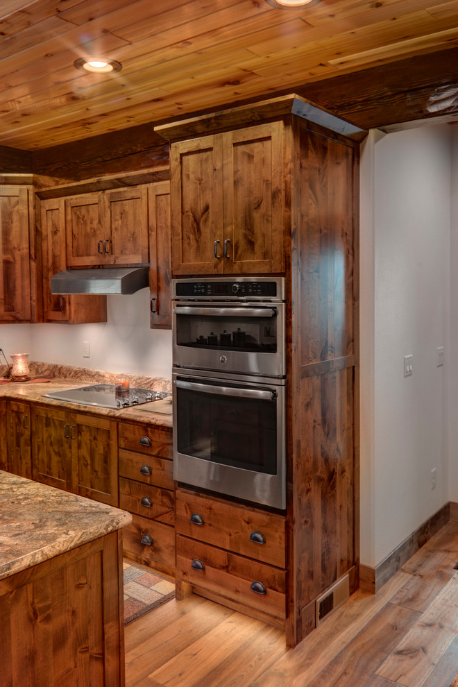 Mid-sized mountain style u-shaped medium tone wood floor eat-in kitchen photo with an undermount sink, shaker cabinets, medium tone wood cabinets, laminate countertops, stainless steel appliances and two islands