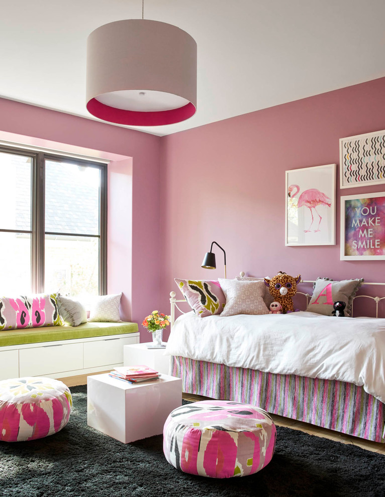 Transitional kids' bedroom in Dallas with pink walls and light hardwood floors for kids 4-10 years old and girls.