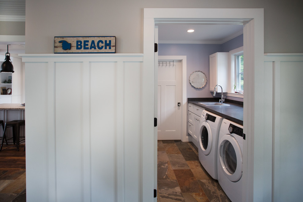 This is an example of a single-wall dedicated laundry room in Other with a drop-in sink, white cabinets, slate floors, a side-by-side washer and dryer and grey benchtop.