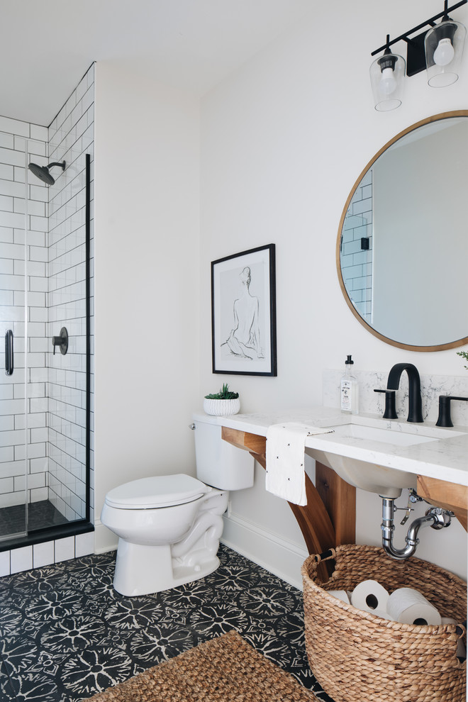 This is an example of a country 3/4 bathroom in Chicago with open cabinets, an alcove shower, subway tile, white walls, an undermount sink, black floor, a hinged shower door and white benchtops.