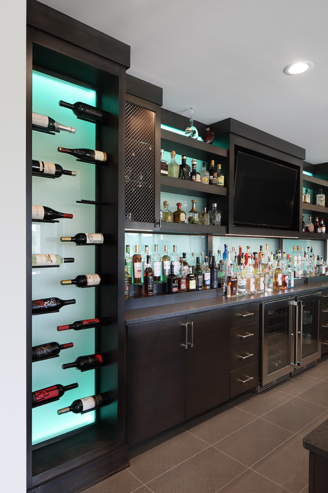 Photo of an expansive midcentury single-wall seated home bar in Milwaukee with an undermount sink, concrete benchtops, glass tile splashback, porcelain floors, grey floor and black benchtop.