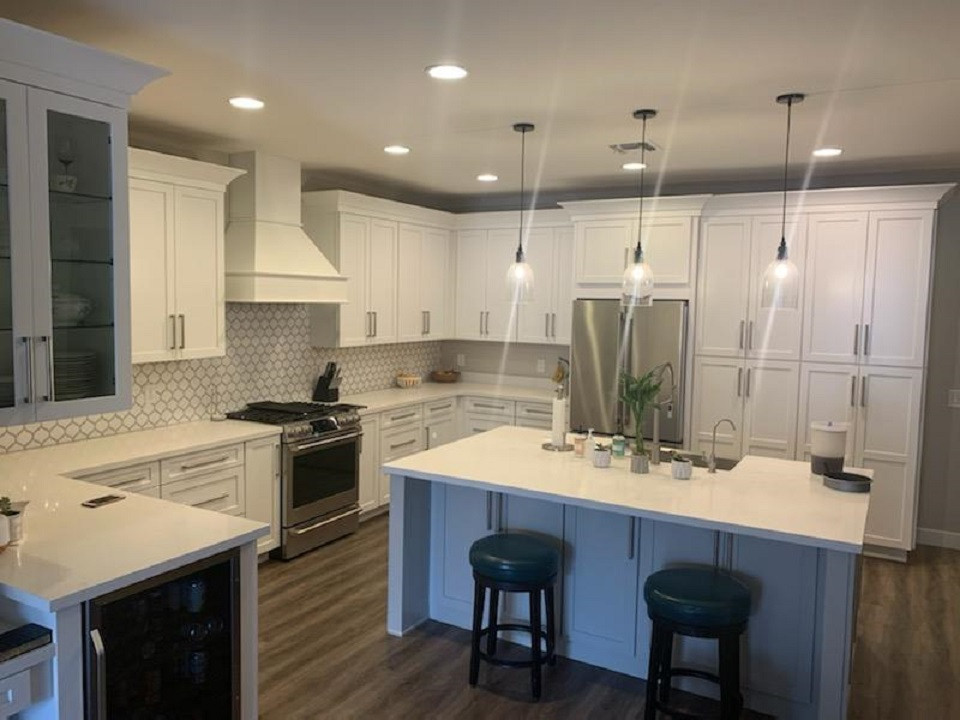 Eat-in kitchen - mid-sized transitional u-shaped laminate floor eat-in kitchen idea in Phoenix with a farmhouse sink, shaker cabinets, white cabinets, quartz countertops, gray backsplash, porcelain backsplash, stainless steel appliances, an island and white countertops