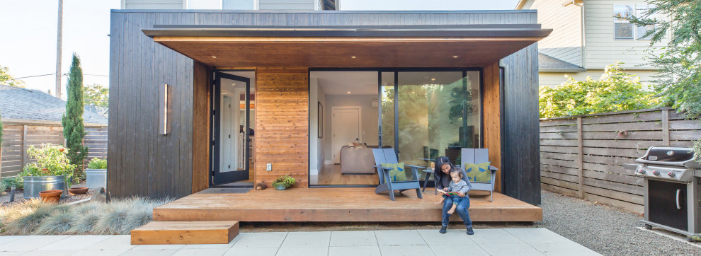 Inspiration for a small modern backyard deck in Portland with with privacy feature and a roof extension.