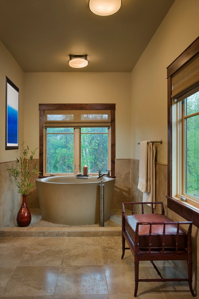 This is an example of a large country master bathroom in Denver with an integrated sink, shaker cabinets, dark wood cabinets, a japanese tub, an alcove shower, a one-piece toilet, beige tile, stone tile, beige walls and travertine floors.