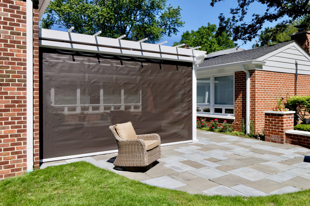 This is an example of a mid-sized contemporary backyard patio in Chicago with natural stone pavers and a pergola.