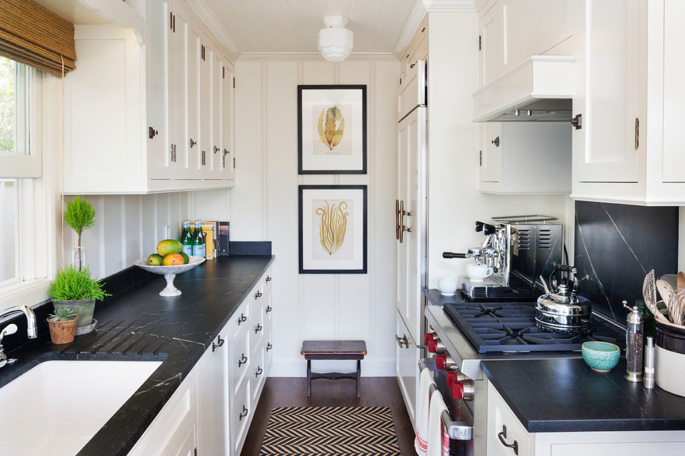 Photo of a small beach style galley kitchen in Orange County with a single-bowl sink, shaker cabinets, white cabinets, black splashback, dark hardwood floors and no island.