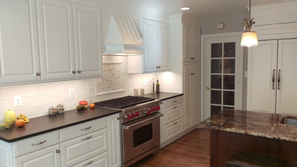 Inspiration for a mid-sized traditional l-shaped open plan kitchen in DC Metro with an undermount sink, raised-panel cabinets, white cabinets, granite benchtops, white splashback, ceramic splashback, stainless steel appliances, medium hardwood floors and with island.