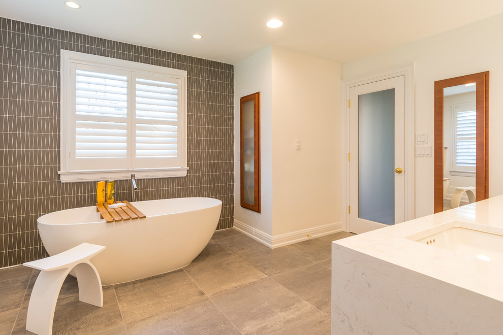 Photo of a large contemporary master bathroom in Indianapolis with a freestanding tub, gray tile, glass tile, grey walls, porcelain floors and grey floor.