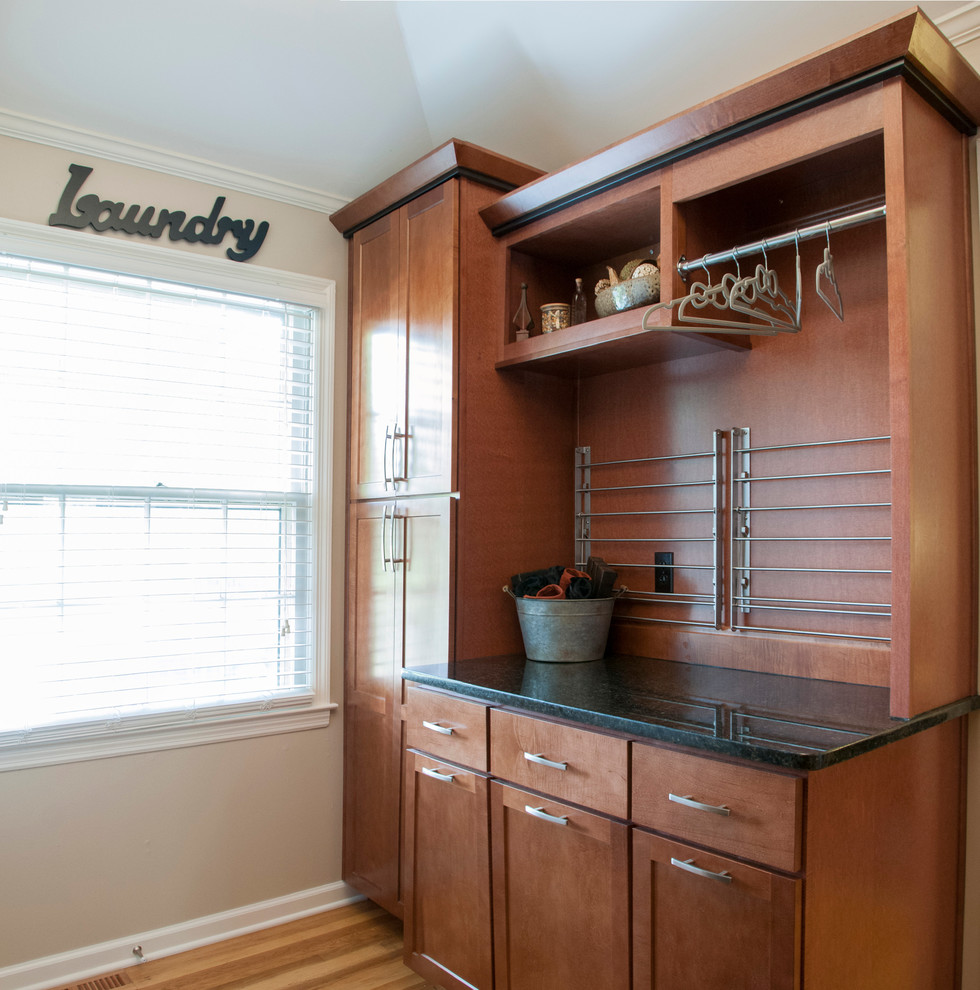 Photo of a mid-sized traditional u-shaped dedicated laundry room in Kansas City with an undermount sink, shaker cabinets, medium wood cabinets, granite benchtops, beige walls, medium hardwood floors and a side-by-side washer and dryer.