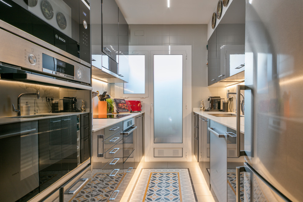 Small eclectic single-wall separate kitchen in Barcelona with an undermount sink, flat-panel cabinets, grey cabinets, quartz benchtops, white splashback, engineered quartz splashback, stainless steel appliances, porcelain floors, grey floor and white benchtop.