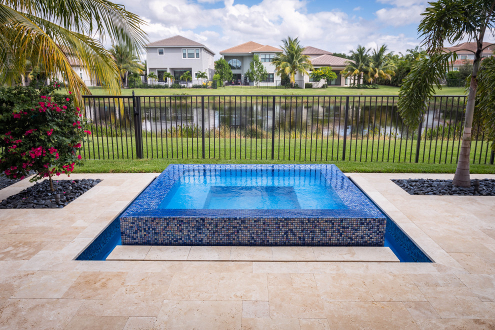 Design ideas for a mid-sized modern backyard rectangular pool in Miami with a hot tub and natural stone pavers.