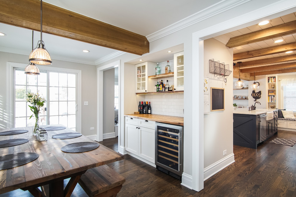 This is an example of a country kitchen in Chicago with a farmhouse sink, shaker cabinets, white cabinets, quartzite benchtops, white splashback, ceramic splashback, stainless steel appliances, dark hardwood floors, with island, brown floor and white benchtop.