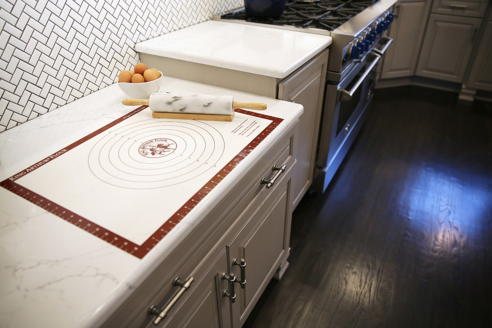 Enclosed kitchen - large transitional l-shaped dark wood floor and brown floor enclosed kitchen idea with raised-panel cabinets, white backsplash, ceramic backsplash, stainless steel appliances and an island