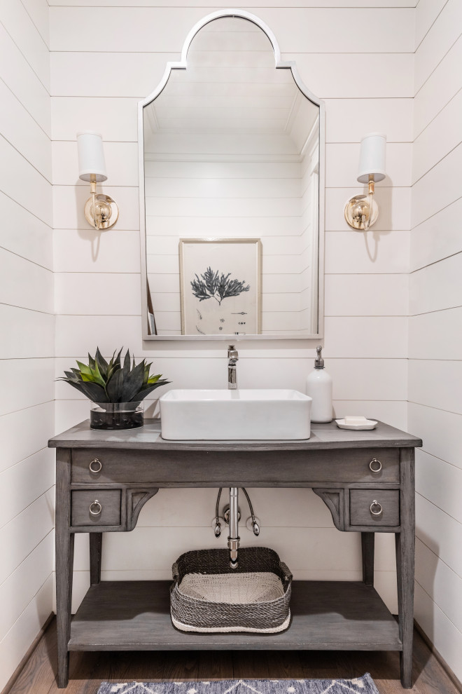 Beach style powder room in Charlotte with open cabinets, grey cabinets, white walls, dark hardwood floors, a vessel sink, brown floor, grey benchtops, a freestanding vanity and planked wall panelling.