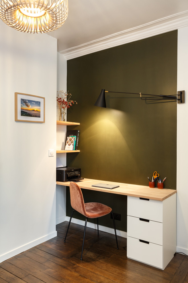 Modelo de despacho contemporáneo pequeño con paredes verdes, suelo de madera oscura, escritorio empotrado y suelo marrón